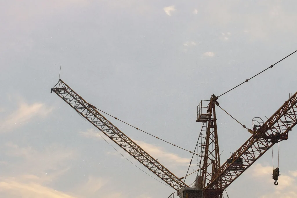 Construction cranes silhouetted against a soft evening sky with light clouds