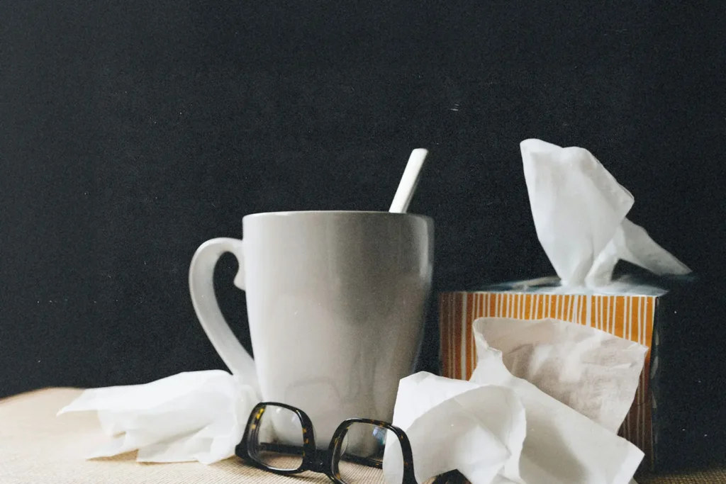 White mug, tissue box, and scattered tissues arranged on a table with a dark background
