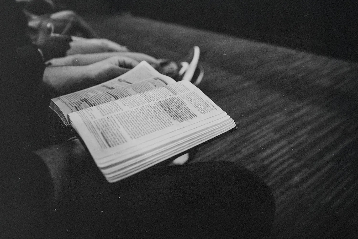 Person holding an open Bible while seated in a quiet setting