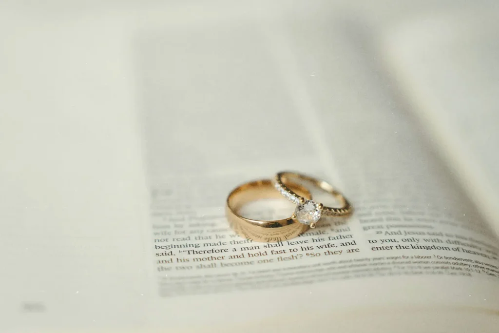 Two gold wedding rings, one with a diamond, rest on the open pages of a Bible