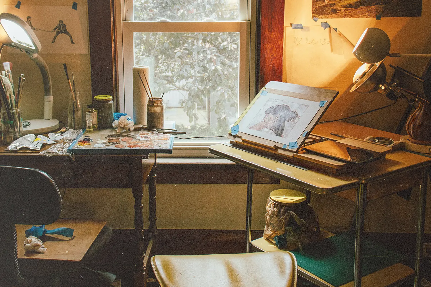 Cozy art studio with drawing desk, paints, and window light