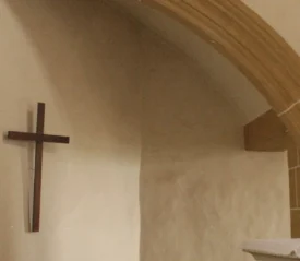 A cross on a wall of a small stone church