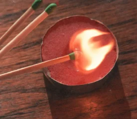 Match lighting a tea light on wooden table