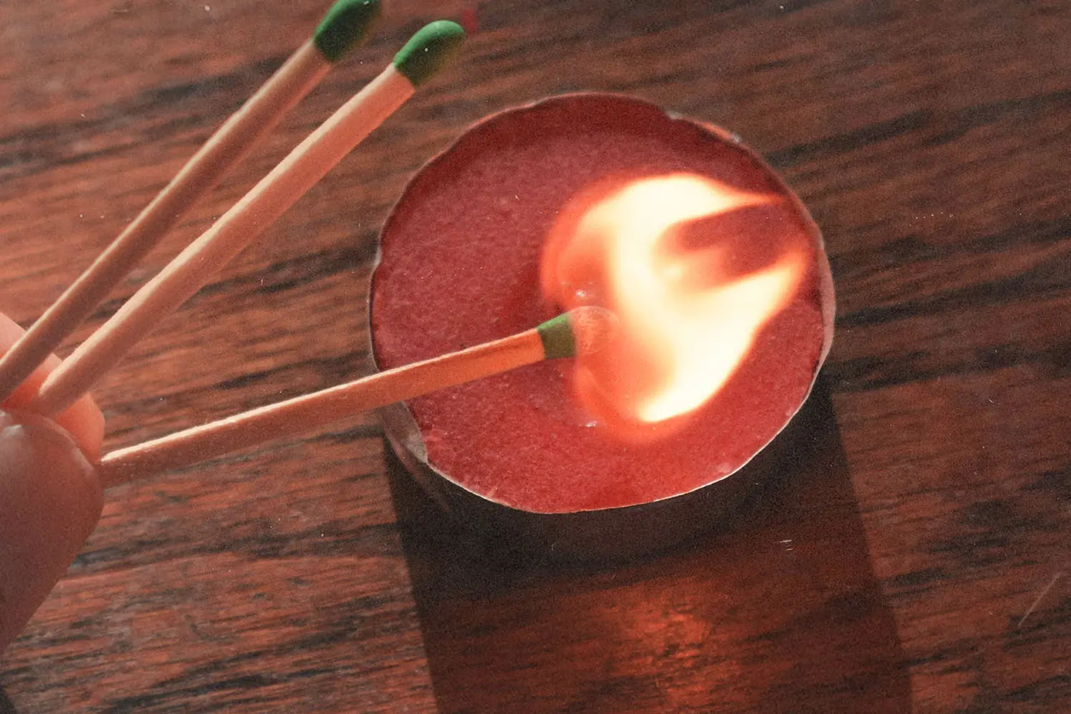 Match lighting a tea light on wooden table
