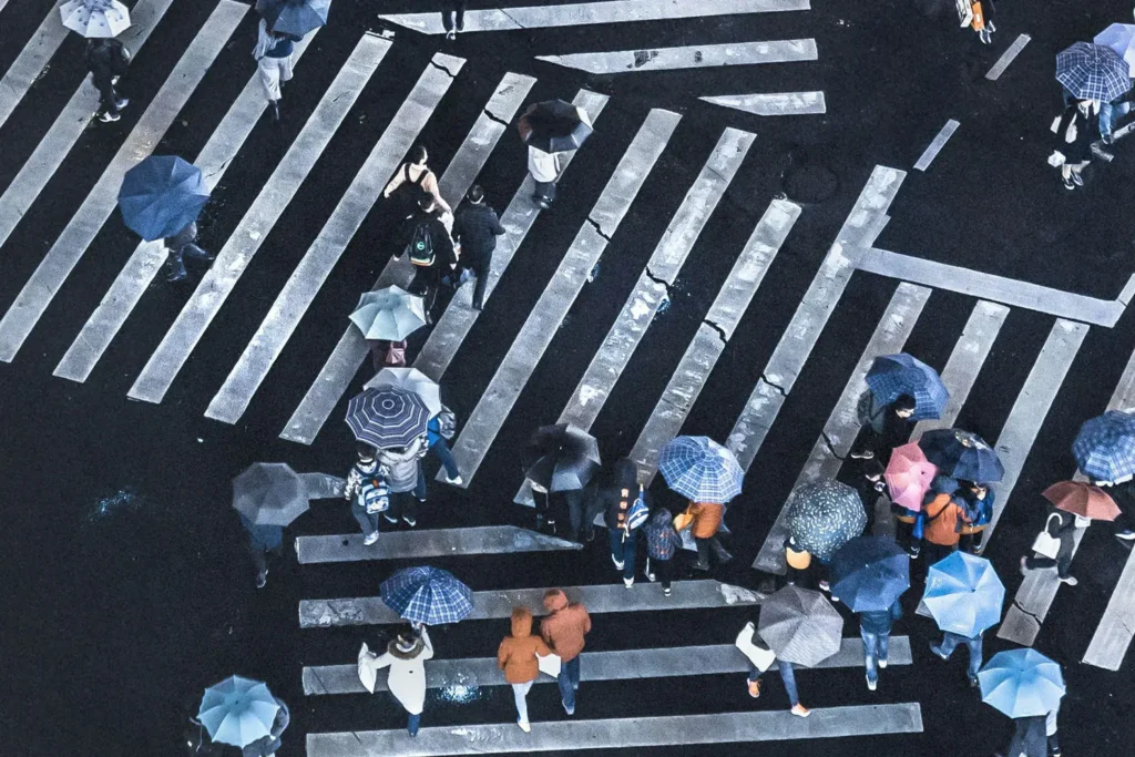 people walking across the crosswalk with umbrellas