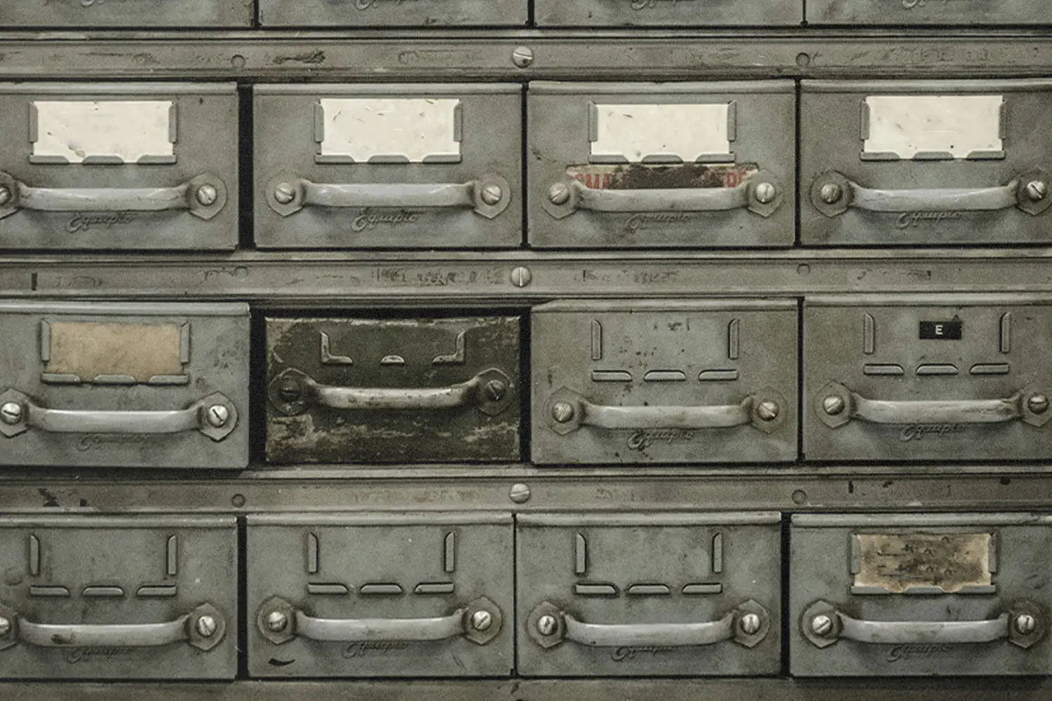 Close-up of an old metal drawer cabinet with worn labels and distressed handles