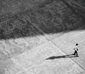A man walking alone, casting a long shadow