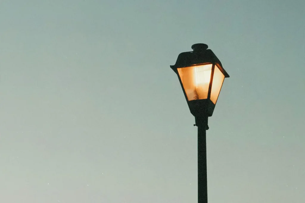 Street lamp lit with a clear sky in the background