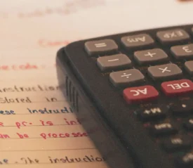 Calculator placed on lined paper filled with handwritten instructions in multiple ink colors