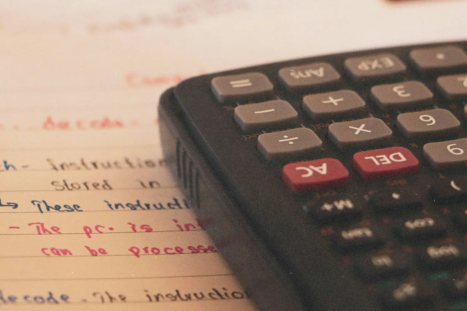 Calculator placed on lined paper filled with handwritten instructions in multiple ink colors