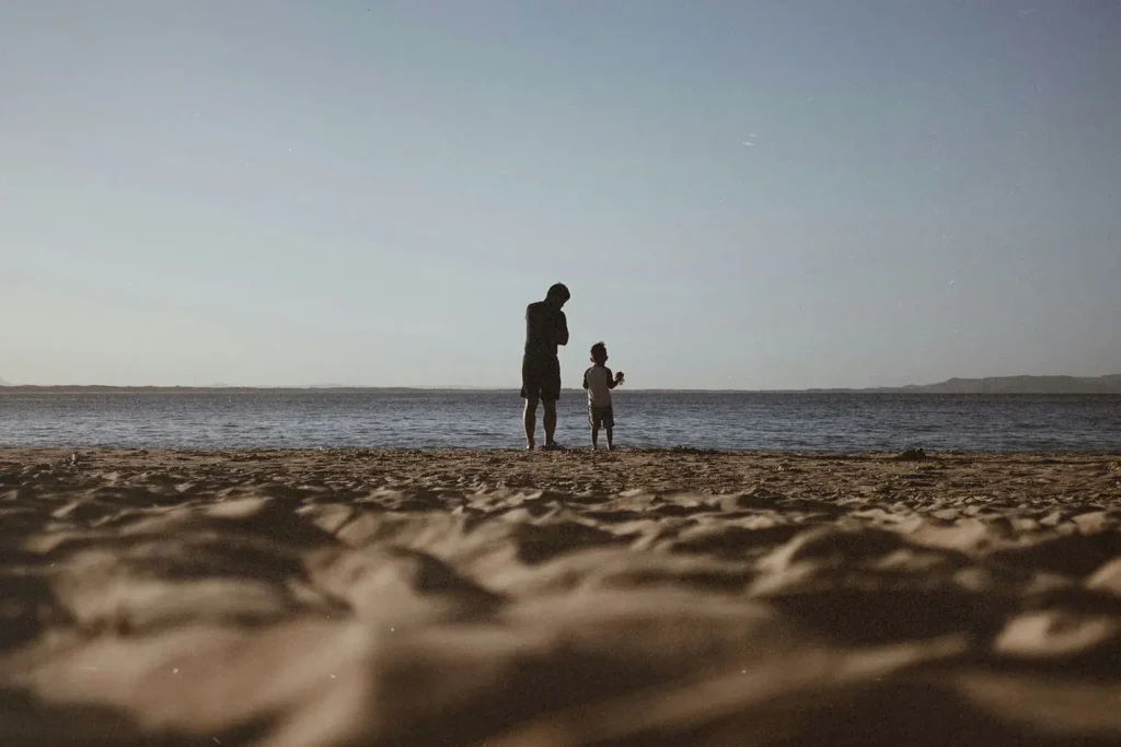 Father and son standing on shore looking out to the sea