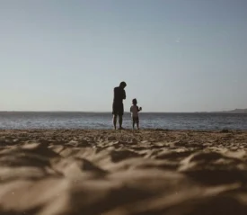 Father and son standing on shore looking out to the sea