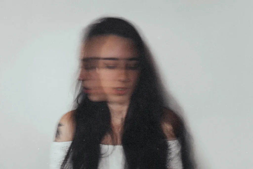 Blurred image of woman shaking her head with her eyes closed
