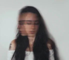 Blurred image of woman shaking her head with her eyes closed