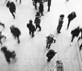 Black and white, blurred, aerial view of crowd of people walking