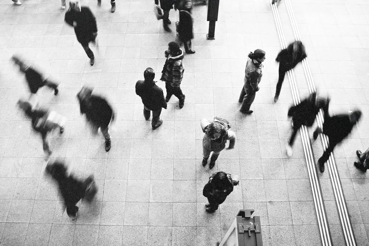 Black and white, blurred, aerial view of crowd of people walking