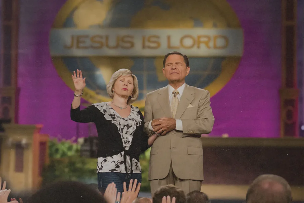 Kenneth and Gloria Copeland standing at the pulpit in prayer