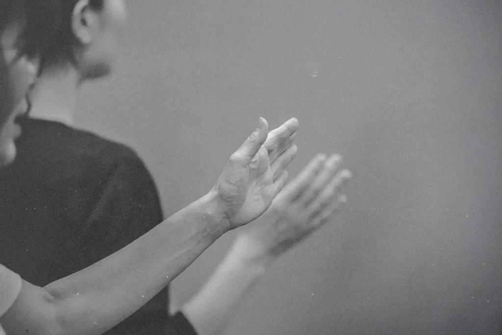 Hands raised in worship or praise during a quiet, reverent moment in a black‑and‑white scene