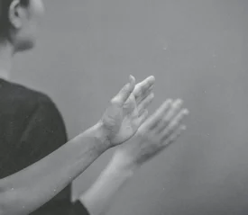 Hands raised in worship or praise during a quiet, reverent moment in a black‑and‑white scene