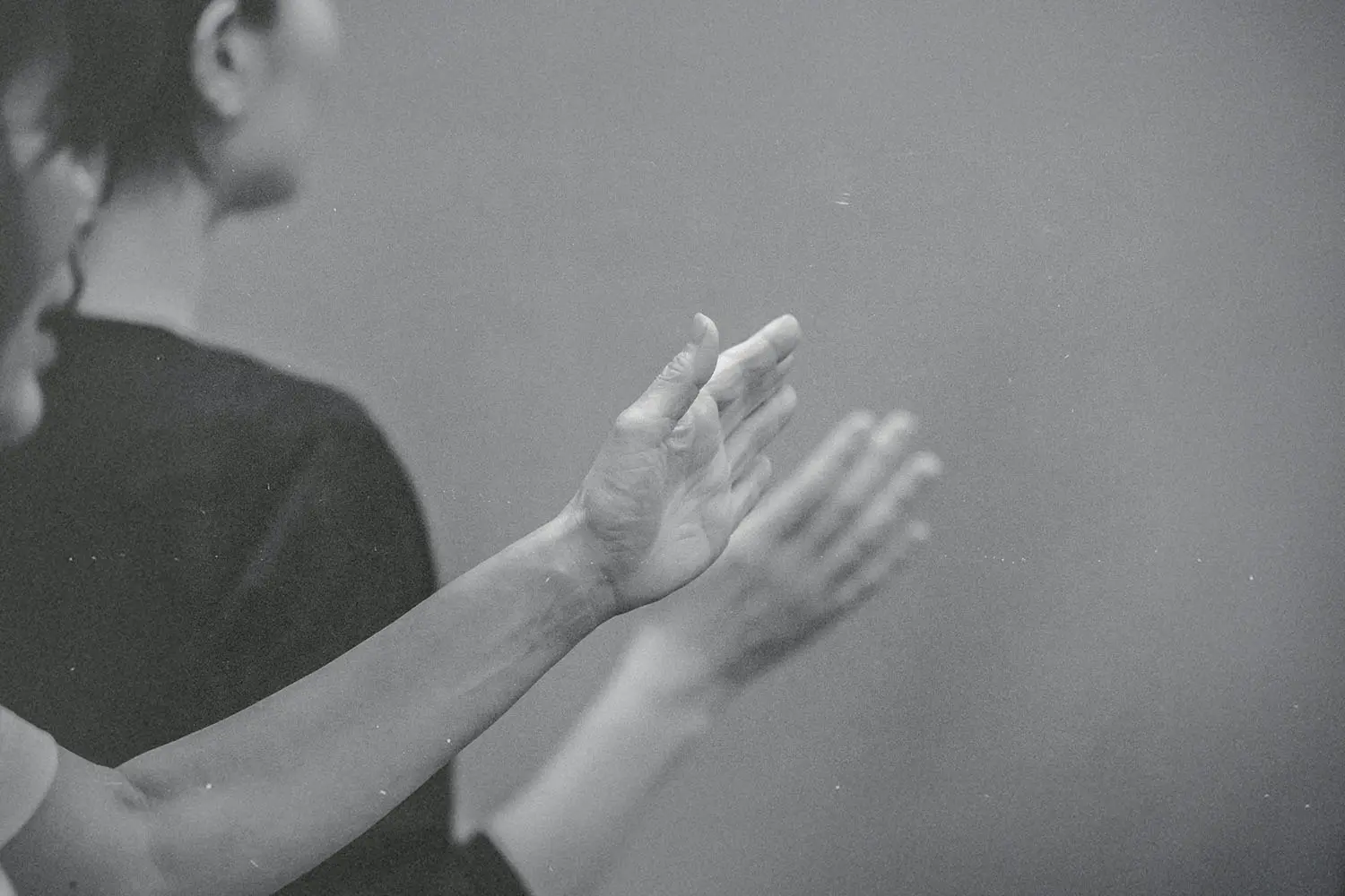 Hands raised in worship or praise during a quiet, reverent moment in a black‑and‑white scene