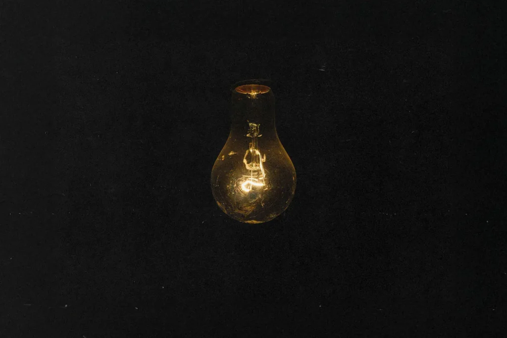 Dark background with a dimly lit light bulb hanging