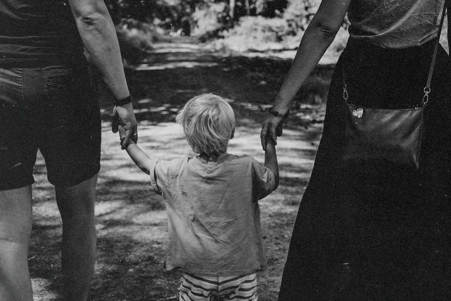 Little boy in the middle of two parents holding each hand