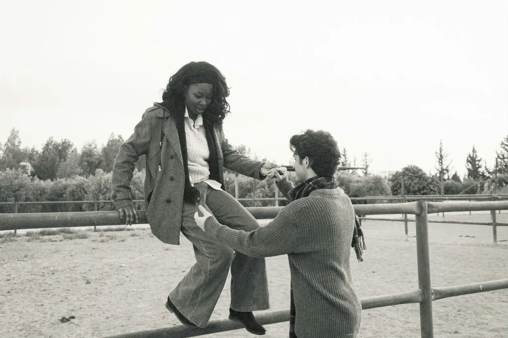 Man helping a woman get down from railing