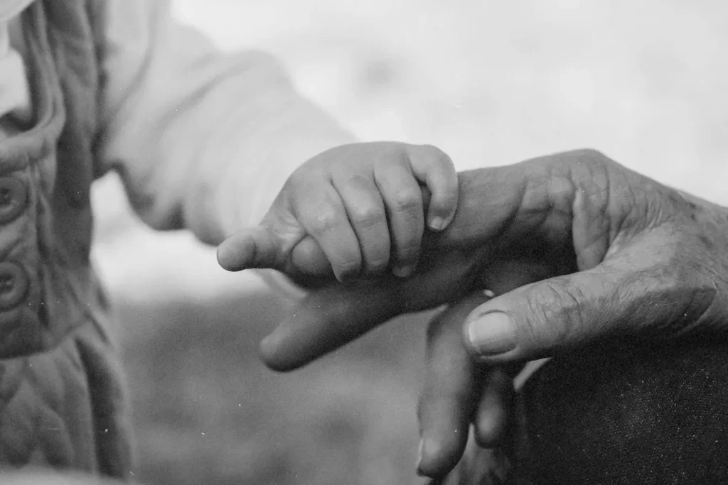 Child's hand grasping an elderly person's finger