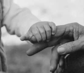 Child's hand grasping an elderly person's finger