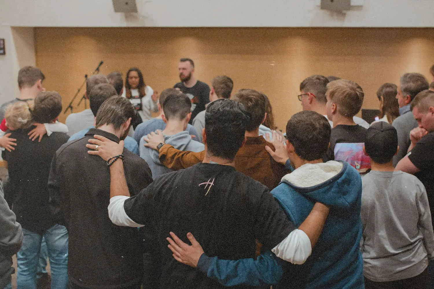 Group of people standing in a circle with arms linked and praying