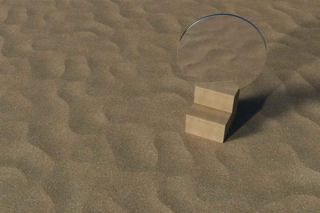 Round mirror placed on a small wooden block in the middle of textured sand, reflecting the surrounding sandy surface