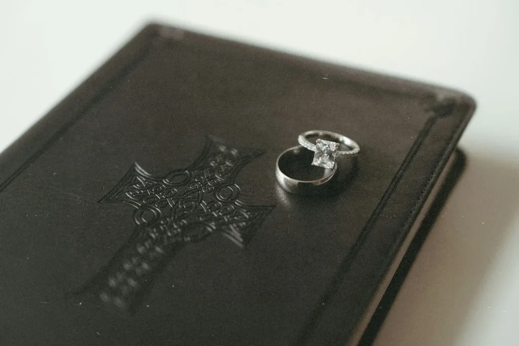 Wedding rings resting on top of a closed leather Bible embossed with a decorative cross