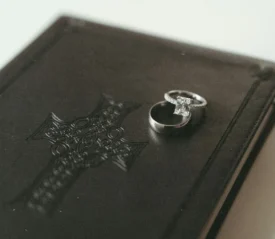 Wedding rings resting on top of a closed leather Bible embossed with a decorative cross