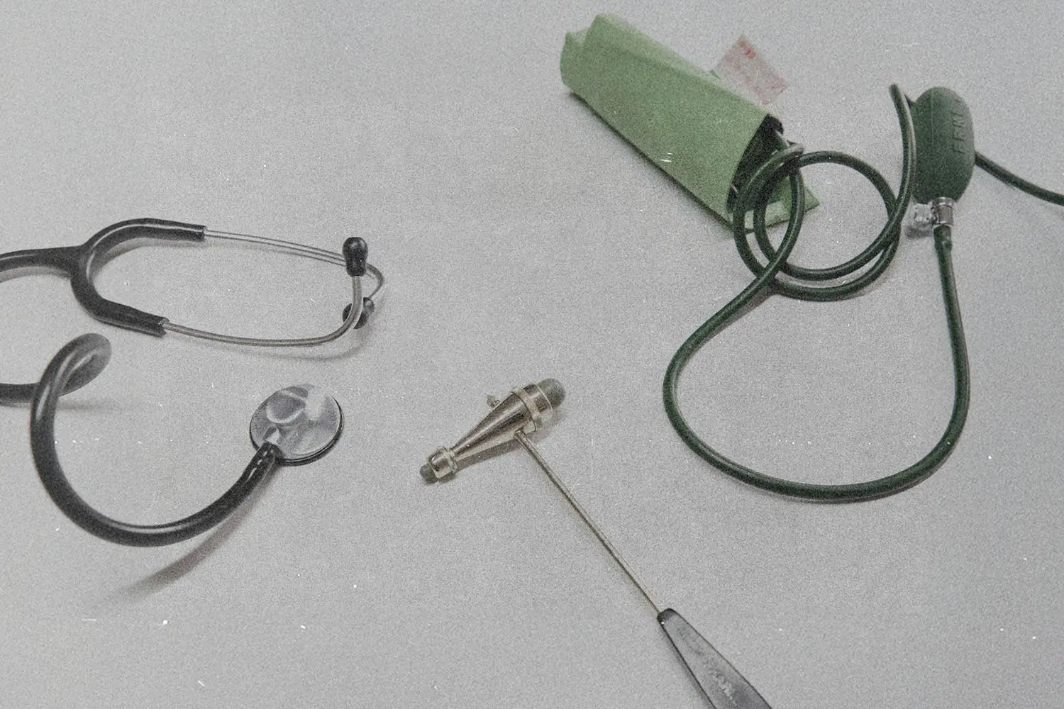 Stethoscope, blood pressure cuff, and reflex hammer arranged on a light surface