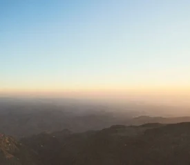 Sunrise casting warm light over distant mountain ridges