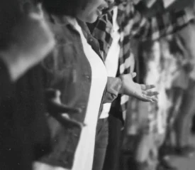 People standing in a row with their arms extended and hands open in a gesture of worship or prayer