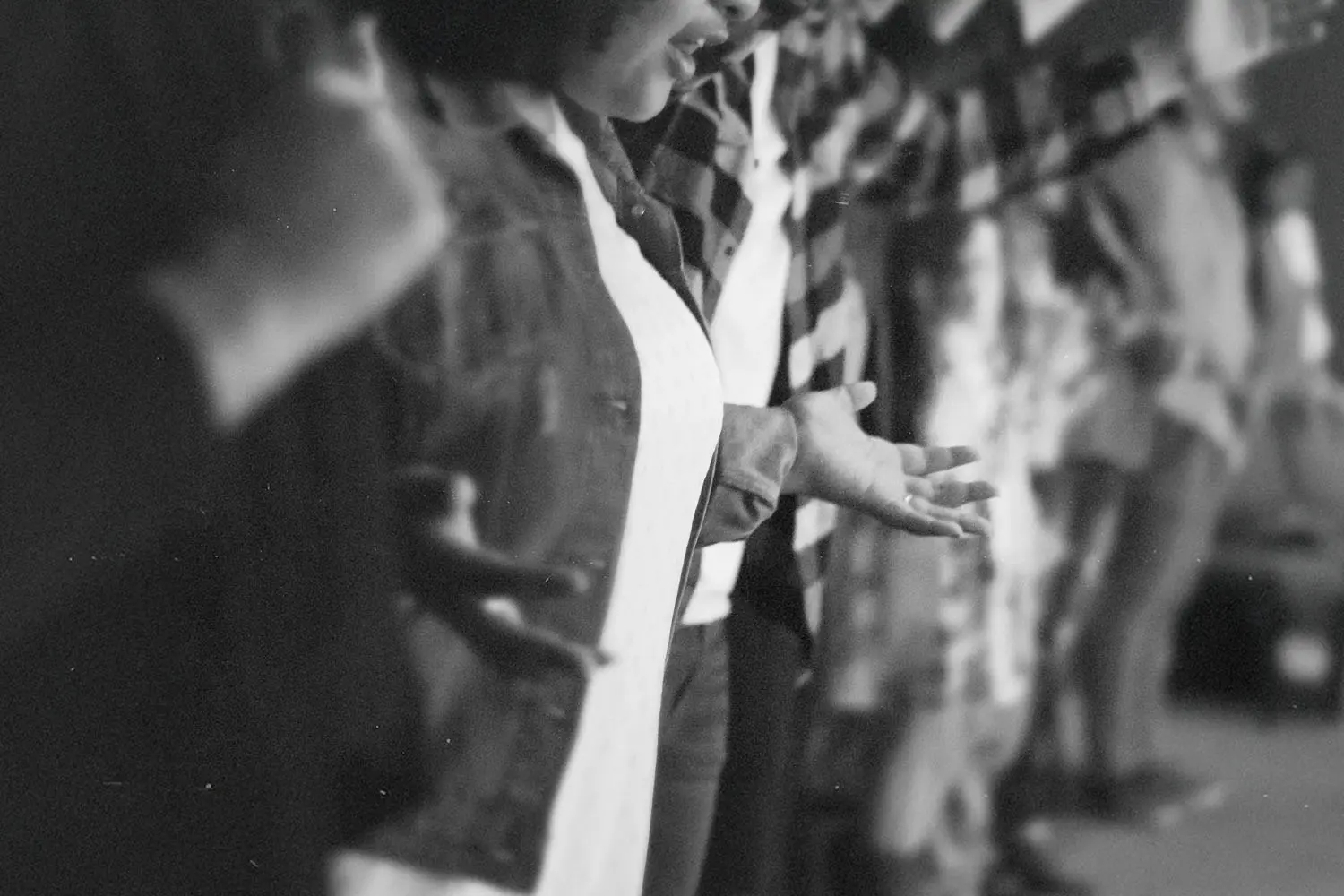 People standing in a row with their arms extended and hands open in a gesture of worship or prayer