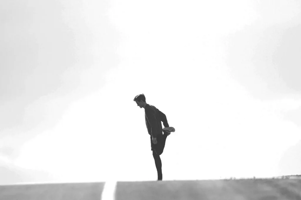 person stretching leg in middle of empty road