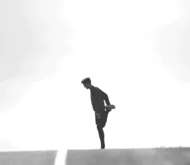 person stretching leg in middle of empty road