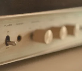 Close-up of a vintage audio receiver showing a metal power toggle switch and several blurred control knobs
