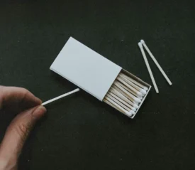 hand lighting a match with the match box