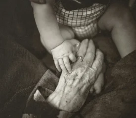 Elderly hand holding baby hand