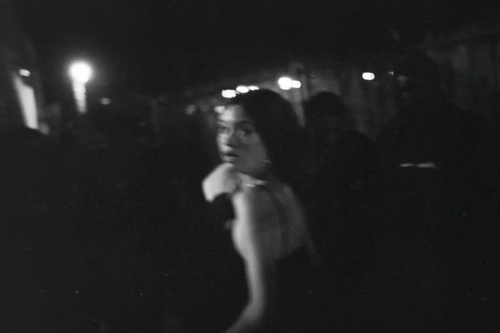 girl in shock running from camera in a darkroom filled with people