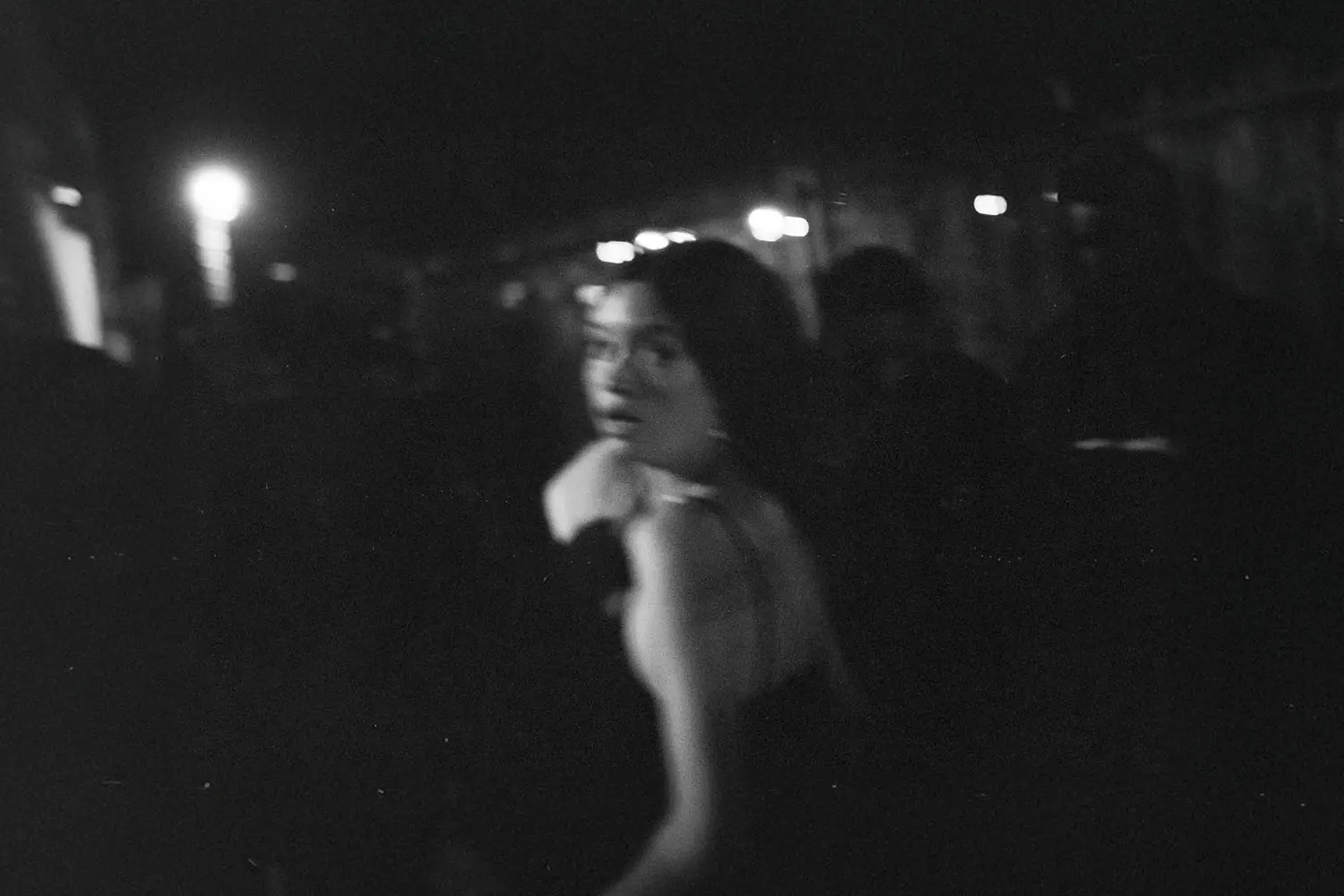 girl in shock running from camera in a darkroom filled with people