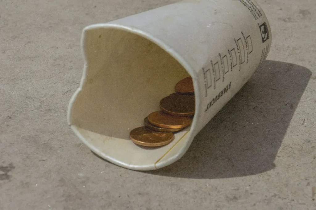 cup laying on ground with loose coins inside