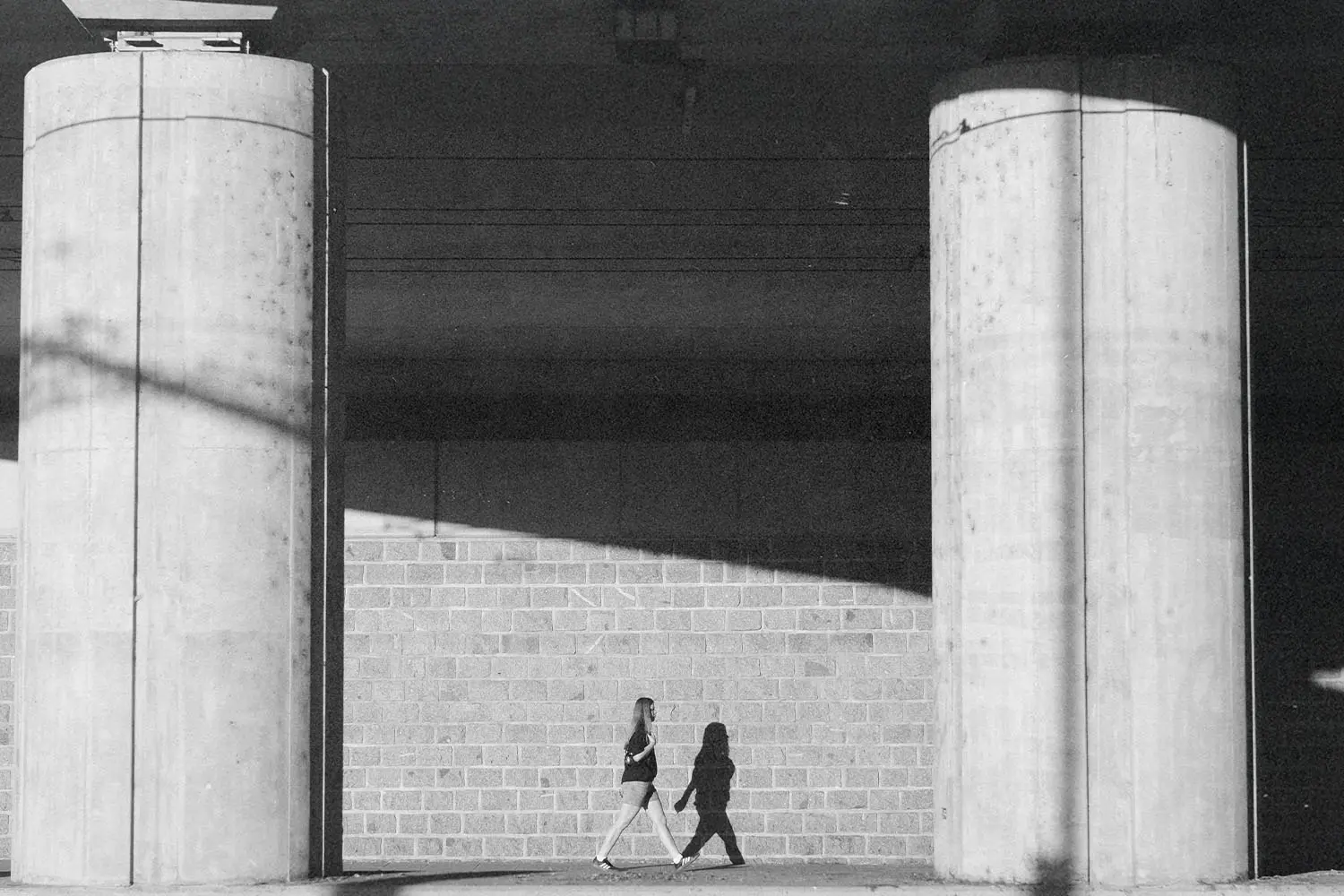 Woman walking through breezeway with two concrete pillars in view