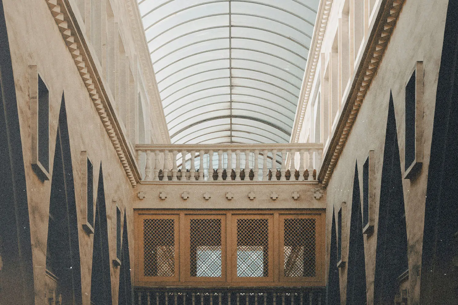 A long interior hallway with tall walls, arched glass ceiling, and symmetrical architectural details