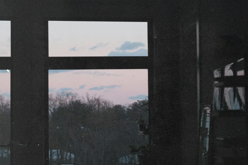 oft pink and blue sunset sky visible through a large window framing distant treetops