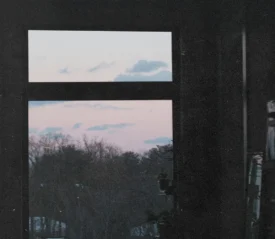 oft pink and blue sunset sky visible through a large window framing distant treetops
