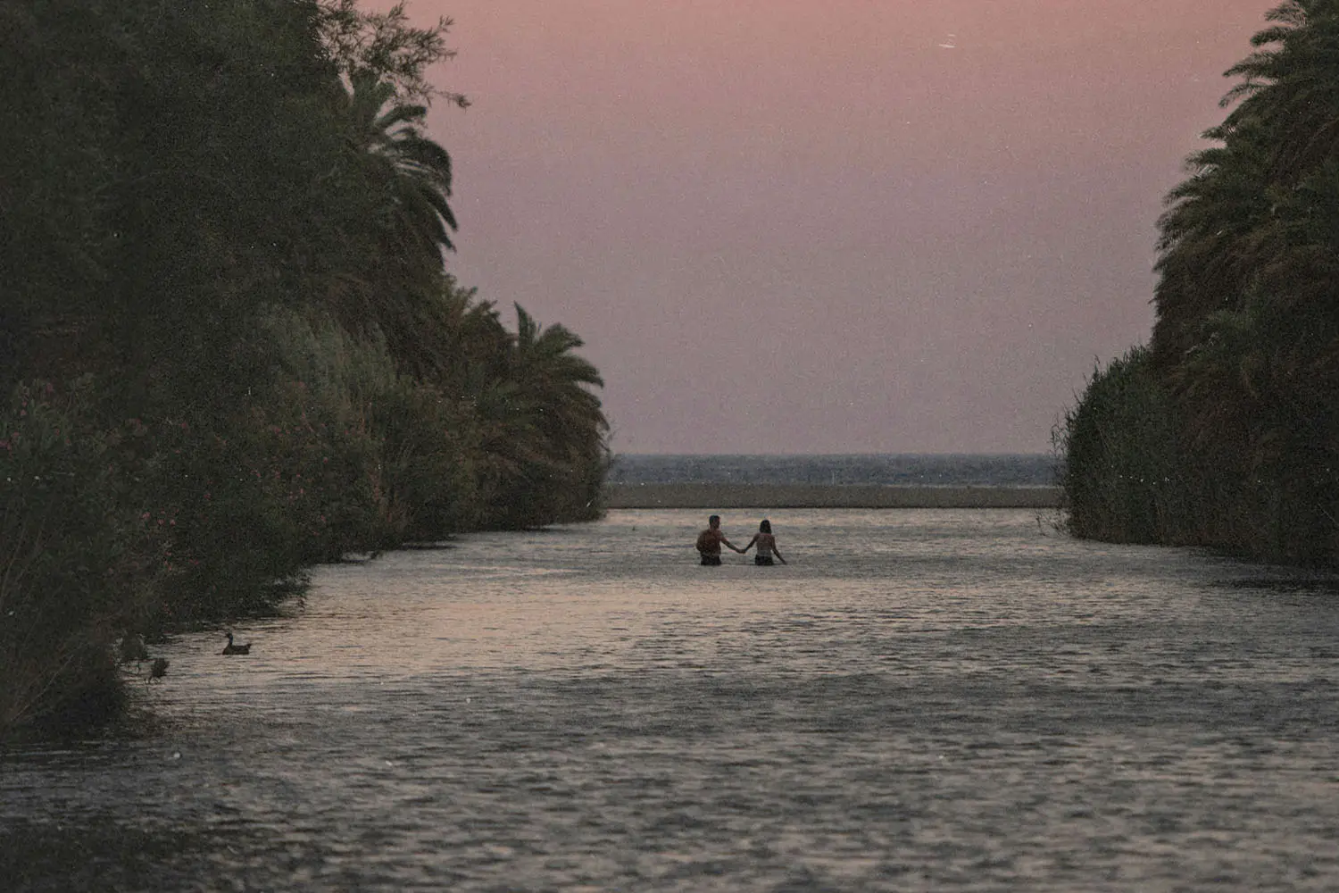 couple walking through water to the beach
